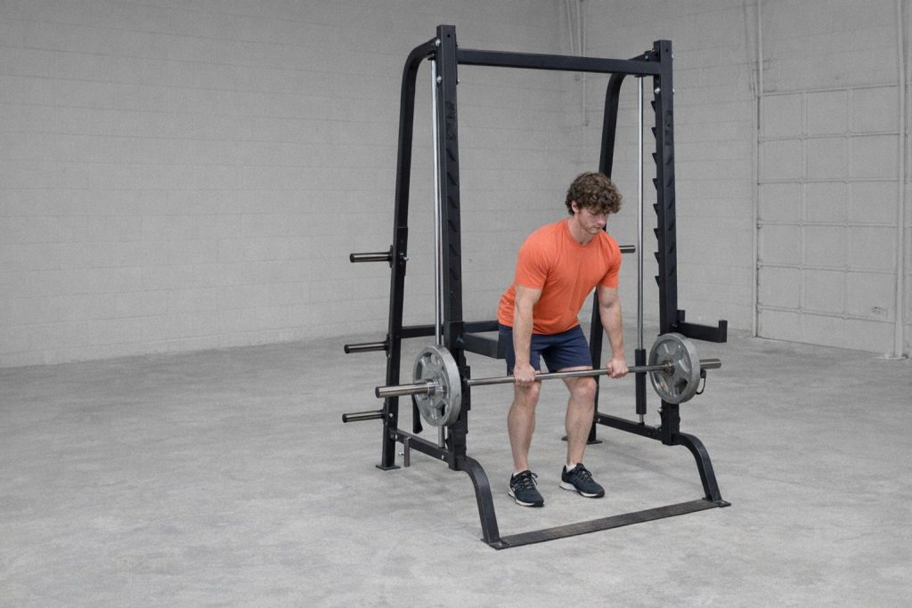 En man utför marklyft med en robust smithmaskin i ett stilrent hemmagym.